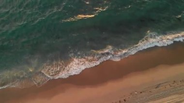 Deniz dalgalarının kumlu sahili gösteren manzaralı bir manzarası.