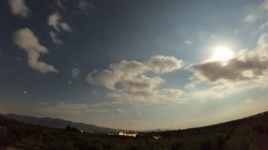 Gece gündüz bulutlu gökyüzünün düşük açılı görüntüsü. Gece ışıkları olan büyük ot ormanlarında.