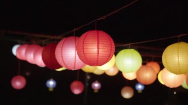 Renkli ışıklı kağıt fenerler rüzgarda sallanan ipten sarkıyor