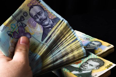 Siyah arka planda bir yığın LEI Romen parasını tutan bir el