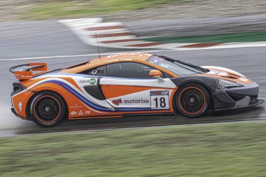 Bulutlu ve yağmurlu bir günde yarış pistinde süper hızlı bir araba, McLaren 570 'ler