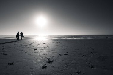 Kum sahilinde yürüyen iki siluet, Penishe, Portekiz, gri pullu