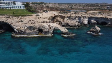 Turkuaz bir denize karşı oteller ve binalarla kaplı kumlu bir sahilin kuş bakışı görüntüsü.