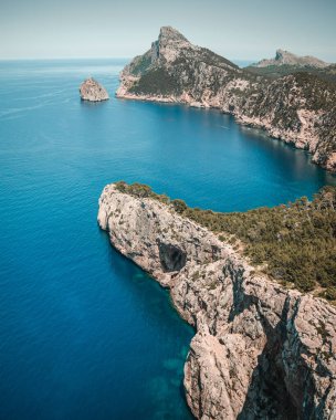 Gökyüzünün altında kayalıkları olan güzel bir deniz manzarası.