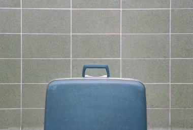 Orta çağ modern fayans duvarına karşı mavi antika bavul.