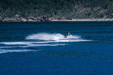 Mavi bir gölde jet ski süren insanların güzel bir fotoğrafı.