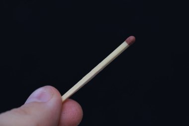 Siyah bir arkaplanda bir kibrit çöpü tutan bir elin yakın çekimi