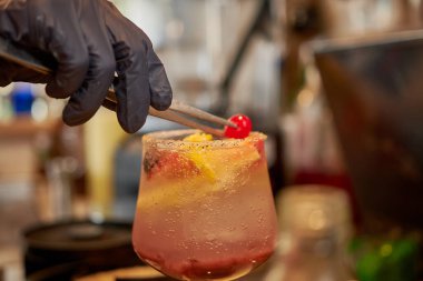 Barmenin elinin vişneli kokteyl süslemesi.