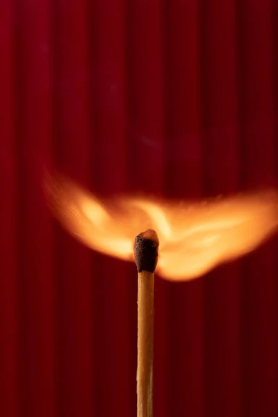 一根被红色背景隔开的燃烧的木制火柴棍的垂直拍 — 图库照片