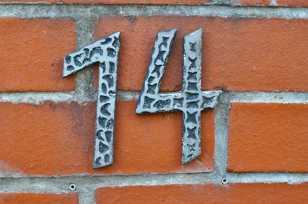 レンガの壁の背景に14番目の金属記号のクローズアップショット — ストック写真