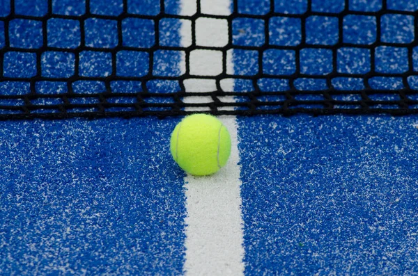 blue paddle tennis court and net with a ball
