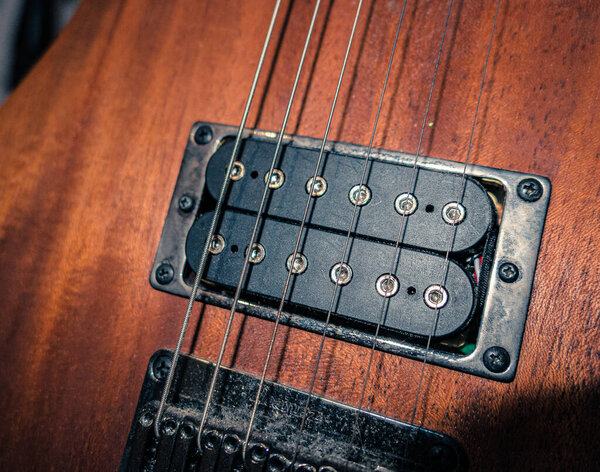 A closeup of the strings of a wooden electric guitar