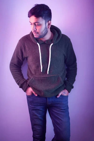 High Fashion male model wearing winter warm clothing in colorful bright neon lights.