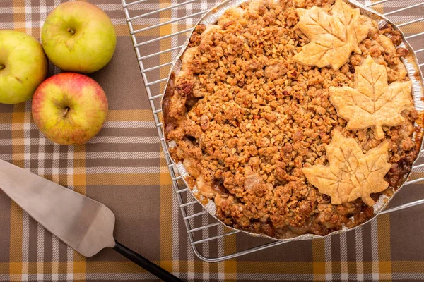 A top view of a baked apple pie with maple leaf decorations.