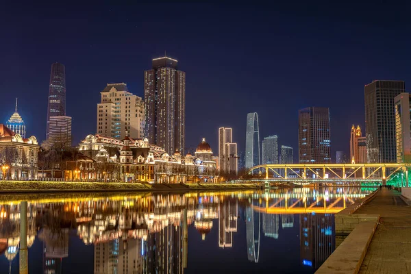 近代的な建物や塔が立ち並び 夜は川が流れる街の風景 — ストック写真