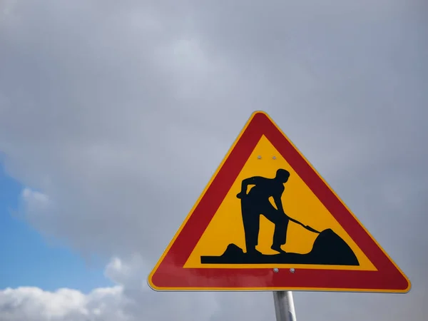 Construction sign against cloudy sky