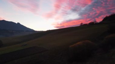 Renkli günbatımında dağlarla ve çayırlarla manzaralı bir manzara.