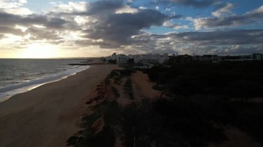 İnsansız hava aracı görüntüleri, Atlantik Okyanusu kıyısında turist kasabası Quareira 'yı çekiyor, turistlerle dolu plajlar. Portekiz, Algarve.