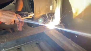 Otomotiv fabrikasında kaynak yapan adamın yakın çekim görüntüleri..