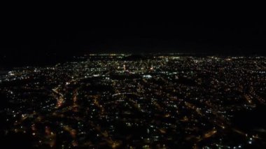 Şehir merkezindeki büyük şehir binalarının üzerinde karanlık bir gökyüzü ve gece manzarası.