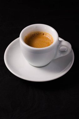 Siyah arka planda beyaz bardakta taze bir kahve.