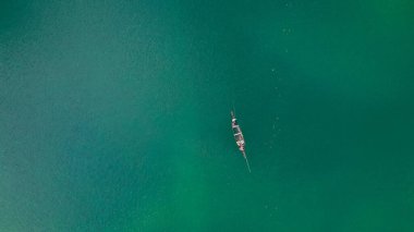 Yeşil sularda yüzen küçük bir teknenin üst görüntüsü.