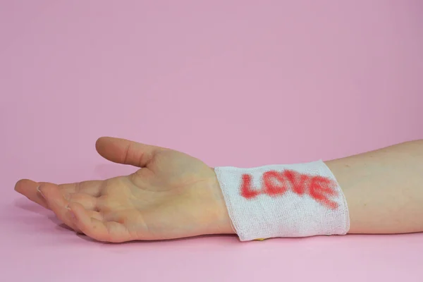 Closeup Shot Hand Bandage Love Written Blood Pink Background — Stock Photo, Image