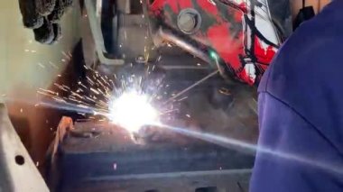 Otomotiv fabrikasında kaynak yapan adamın yakın çekim görüntüleri..