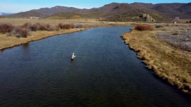 Bir dağ deresi bölgesinde balık tutan bir adamın insansız hava aracı görüntüsü.