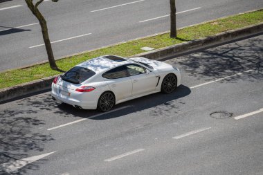 Lizbon sokaklarında beyaz Porsche Panamera marka lüks bir arabanın fotoğrafı.