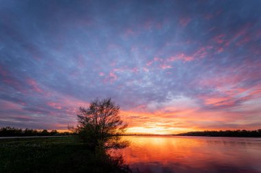 Akşamları bir nehrin üzerinde renkli bir günbatımının güzel bir görüntüsü.