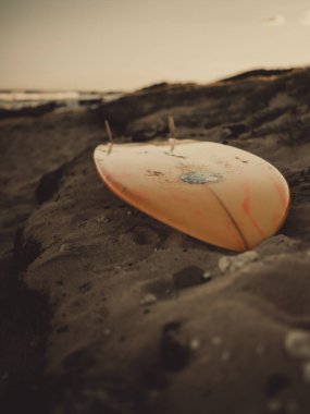 Sahildeki turuncu sörf tahtasının dikey görüntüsü.