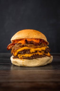 Tahta bir masada lezzetli bir burgerin dikey çekimi.