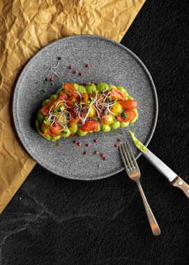 Avokado püresi ve sebzeli ızgara ekmeğin dikey yakın çekimi. Lezzetli yemek..