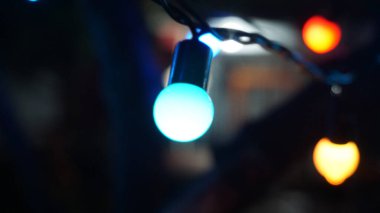 Açık hava sicim lambalarının bulanık arkaplandaki mavi ampulüne yakın çekim