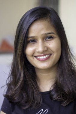 Kameraya gülümseyen genç ve güzel bir kadının dikey yakın çekimi..