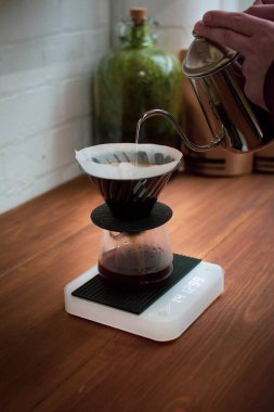 Kahve makinesinin üzerine kaynamış su döken bir erkeğin dikey çekimi.