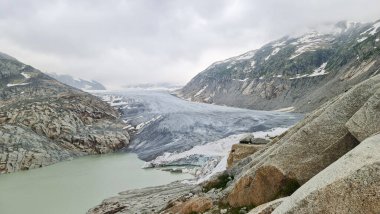 Dağlarda kasvetli bir kış günü. Karlı dağlarla çevrili küçük bir gölet.