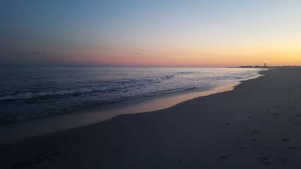 夕阳西下的海滩美景 远处有座灯塔 — 图库照片