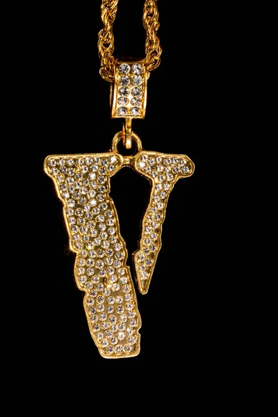 A closeup of a golden V letter on a chain necklace