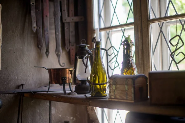 A closeup shot of small chest boxes, candle bottle stand, and old gas lamp on the side of a window