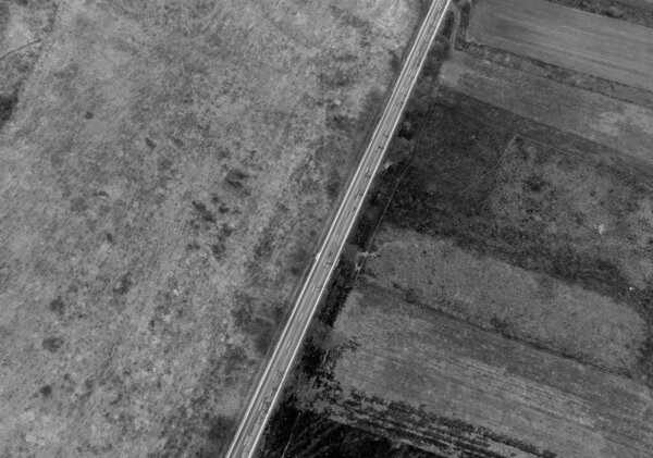 an aerial view of a straight road on a field in black and white