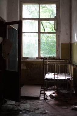 Pripyat 'ta paslı yatağı, kirli duvarları ve pencereleri olan terk edilmiş bir oda.