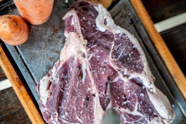 Tahta bir masanın üzerinde havuçlu çiğ bifteğin üst görüntüsü.