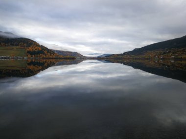 Kasvetli bir günde bulutlu gökyüzünü yansıtan güzel bir göl.