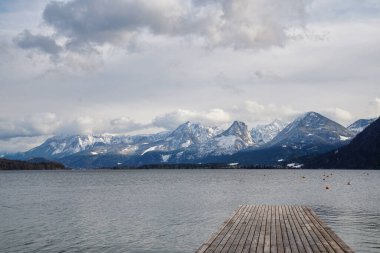 Avusturya 'daki Wolfgangsee gölünün manzarası bulutlu bir arka planda dağlarla çevrili.