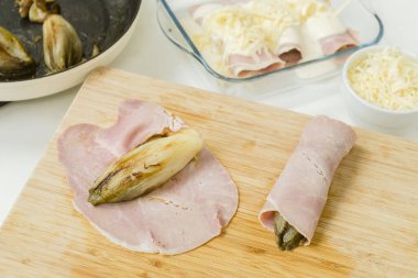 Belçika 'nın klasik yemeği Chicon gratin, ahşap bir tahtaya sarılmış hindibalı.