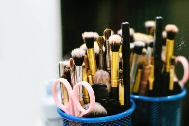 Makyaj fırçası, makas ve tarağın aynaya yakın çekim görüntüsü.