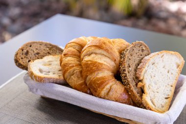 Ekmek parçaları ve kruvasan kumaş tabakta açılı bir çekim..