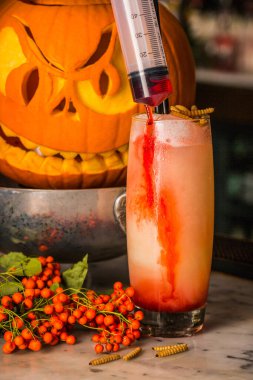 Kızgın suratlı balkabağının arka planında taze rowan kokteyli.